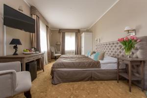 a bedroom with a bed and a desk with flowers on it at Riviera Resort Airport Modlin in Olszewnica Nowa