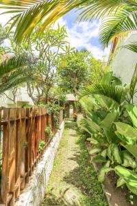 a path through a garden with trees and a fence at Sampian Cottages Bingin in Uluwatu