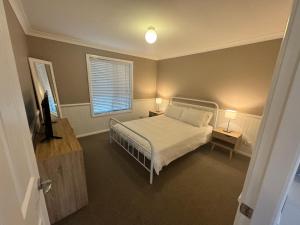 a bedroom with a bed and two lamps and a window at Singleton Rose Cottages in Singleton