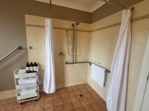a bathroom with a shower with a shower curtain at Singleton Rose Cottages in Singleton +32 photos