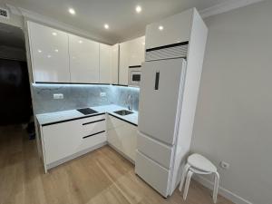 a white kitchen with a refrigerator and a stool at Mirador de Sanlucar 3 in Sanlúcar de Barrameda