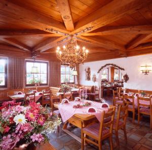 a dining room with tables and chairs and a chandelier at Landgasthof Sonnenhof in Klais