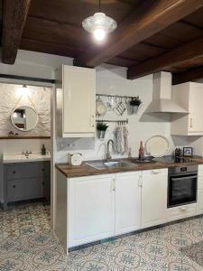a kitchen with white cabinets and a sink at Thatched cottage in Dörgicse