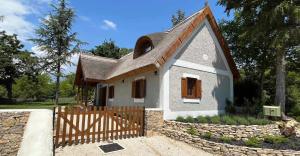 a small white house with a wooden fence at Thatched cottage in Dörgicse
