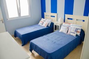 two beds in a room with blue and white stripes at Mi casita de la playa in Arrieta