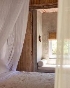 a bedroom with a window and a bed with a curtain at Sampian Cottages Bingin in Uluwatu