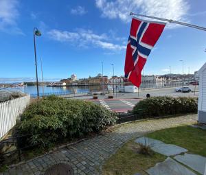 a flag flying on a flag pole next to a body of water at Unique 200-year old tiny house in Old town in Stavanger