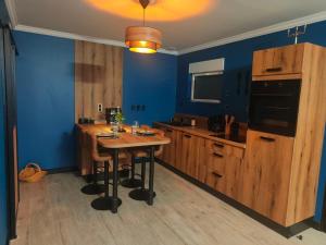 a kitchen with a wooden table and blue walls at Ô bonheur du paon in Arques +11 photos