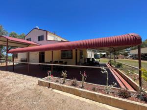 a building with a red roof and some plants at Springfield Stay - Don-gara Unit in Port Denison