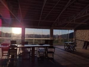 a large room with a table and chairs and windows at Loft 2 Sítio Cachoeiras do Caledonia in Nova Friburgo