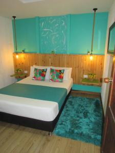 um quarto com uma cama e uma parede azul em The Garden Lleras 10 em Medellín