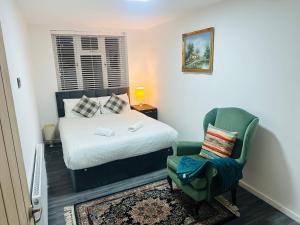 a small bedroom with a bed and a chair at London Comfort Apartment in Fairlop Station