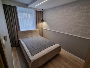 a small bedroom with a bed and a window at Apartament Faleza in Rewal