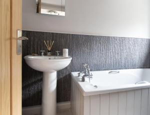 La salle de bains est pourvue d'un lavabo et d'une baignoire. dans l'établissement No33 HILLVIEW LODGE BOUTIQUE COTTAGE, à Brancaster