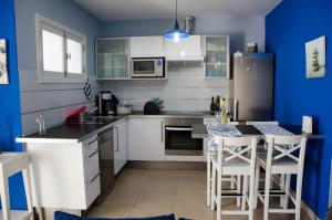 a kitchen with white cabinets and a blue wall at Mi casita de la playa in Arrieta