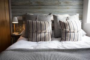 a bed with striped pillows and a wooden headboard at No33 HILLVIEW LODGE BOUTIQUE COTTAGE in Brancaster
