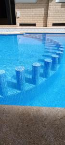 a blue swimming pool with four pillars in it at Le Martil Plage wifi Fibre in Martil