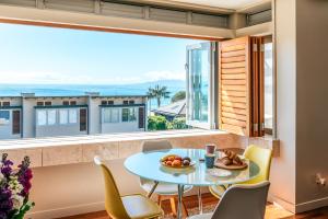 a dining room with a table and chairs and a large window at The Sands Apartment 6 - Stay Waiheke in Waiheke Island