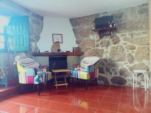 a living room with chairs and a stone fireplace at Casa da Calçada in Arcos de Valdevez