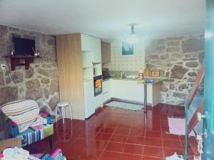 a kitchen with stone walls and a red tile floor at Casa da Calçada in Arcos de Valdevez