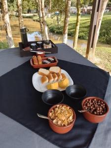 Una mesa con un plato de comida y tazones de comida. en Chalé Hospedagem Ecológica, en Ribeirão Pires