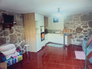 a kitchen with stone walls and a red tile floor at Casa da Calçada in Arcos de Valdevez +3 photos