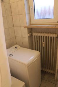 a bathroom with a toilet and a window and a radiator at Apartments Eichenweg in Rednitzhembach