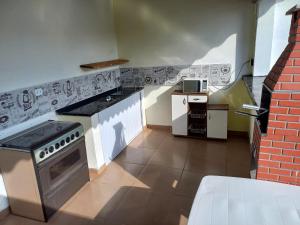 a kitchen with a stove top oven next to a brick wall at Ar condicionado ! Pousada familiar natureza Rustic in Ilha Comprida