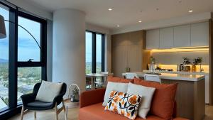 a living room with a couch and a kitchen at Sky One Harmony in Box Hill