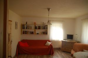 een woonkamer met een rode deken op een bank bij Ferienwohnung Katzstein in Cunnersdorf