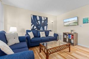 a living room with a blue couch and a coffee table at Modern Condo Just Steps from the OC Boardwalk in Ocean City