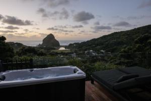 uma banheira num deque com vista para o oceano em The Little Louise's Luxury Romantic Retreat with Iconic Piha Views em Piha