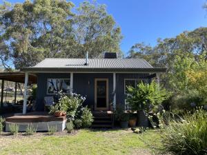 ein winziges Haus mit einer Veranda im Hof in der Unterkunft Blue Gate Cottage in Indigo Upper