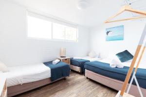 two beds in a room with white walls and a window at Shoalhaven Heads Motel in Shoalhaven Heads