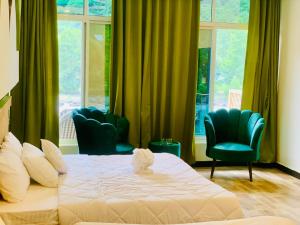 a bedroom with a bed and two chairs and windows at Chinar Resort Keran Neelam Valley in Shāhkot