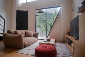 a living room with a couch and a large window at The Sikarim Waterfall View Villa in Kejajar