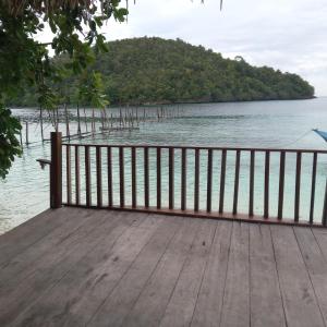a wooden deck with a fence next to the water at Yen Bainut Homestay in Fam