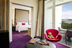 a hotel room with a red chair and a bedroom at Hard Rock Hotel Pattaya - SHA Extra Plus in Pattaya