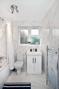 a bathroom with a toilet and a sink and a window at Luxurious apt Zone 2, one stop London Bridge! in London