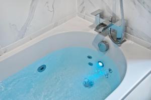 a bath tub filled with blue water with a faucet at Luxurious apt Zone 2, one stop London Bridge! in London +41 photos
