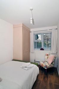 a bedroom with a bed and a chair and a window at Luxurious apt Zone 2, one stop London Bridge! in London
