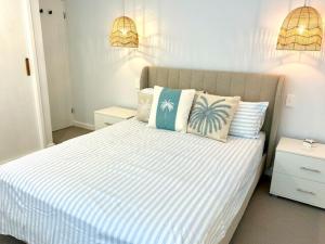 a bedroom with a large white bed with pillows at Stunning Family Home with Tropical Garden in Warriewood