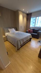 a bedroom with a large bed and a couch at Loft Studio bem localizado e novinho in Passo Fundo