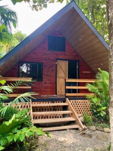a red house with a wooden door and a porch at Cabaña Vacal Wifi, beach front #2 in Uvita +28 photos
