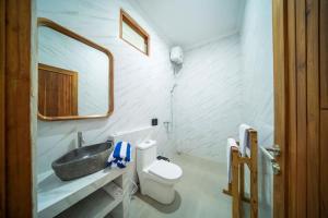 a bathroom with a sink and a toilet and a mirror at D'Gangga Residence By Bali Cabin in Kerobokan +12 photos