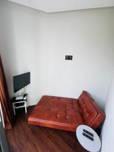 a brown leather couch in a living room with a tv at Embun Pagi villa - Habitat 110 in Batu