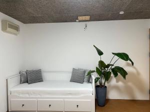 a room with a white bed with a potted plant at Sunshine in Tokyo