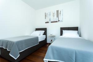 dos camas sentadas una al lado de la otra en una habitación en Deluxe Neli Apartments, en Zadar