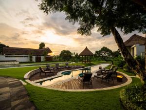 a resort with a pool with chairs and a gazebo at The Samata by LifestyleRetreats in Sanur