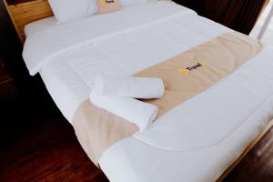 a white bed with two rolled towels on it at Dieng Khatulistiwa By Travelink in Diyeng +8 photos